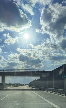 Highway road under overpass with dramatic clouds and bright sun rays in blu.. 写真素材