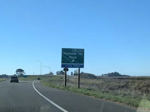 Highway running through open fields with large green Humboldt Hill Road sign Stock Photos