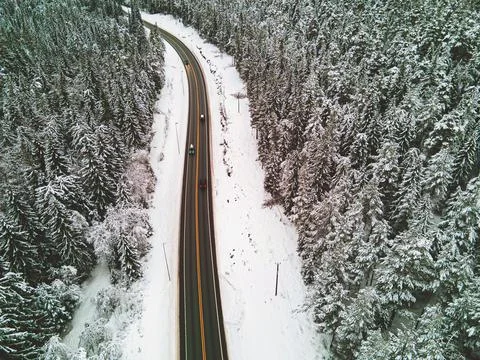 Highway running through a pine forest covered in snow in winter. Stock Photos