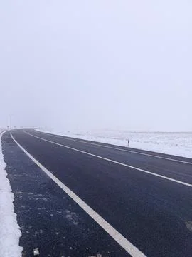 A highway with snow falling around it. Foggy and cold weather. Stock Photos