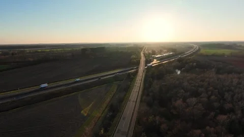 Highway through countryside during sunset with golden sunlight over rural fields Vídeo Stock 324637102