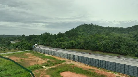 Highway traffic flows alongside a lush green forest landscape 库存影片 337330067