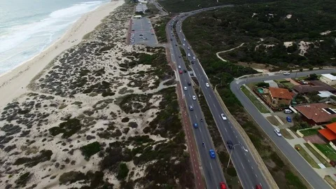 Highway with traffic next to beach flyover aerial footage - left hand drive Stock Footage 107532719
