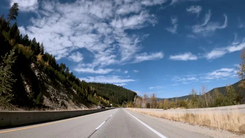 Highway traffic on a summer day between rocky mountains and hills Stock Footage 142475216