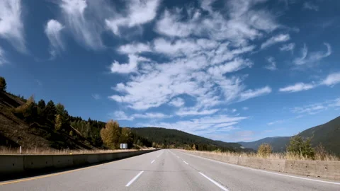 Highway traffic on a summer day between rocky mountains Stock Footage 142475632