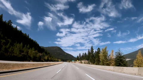 Highway traffic on a summer day between mountains and hills covered with tree Stock Footage 142476068