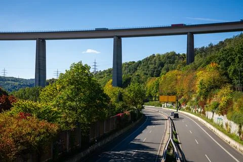 Highway under tall bridge with forest and blue sky. Stock Photos