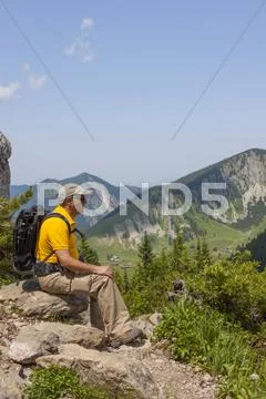 Hiker, 56 years, sitting on rocks enjoying the view, taubenstein near spitzin Stock Photos