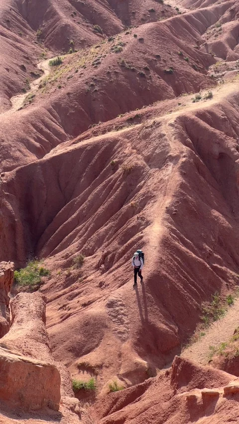 A Hiker Adventurously Exploring the Stunning and Vibrant Red Terrain Stock Footage 281508663