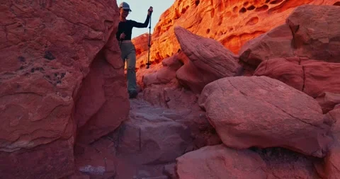 Hiker Ascends Through Red Rock Canyon at Sunset Stock Footage 323800292