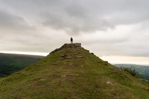 A hiker, back to camera, standing on a hill. Looking out on the countryside Stock Illustration