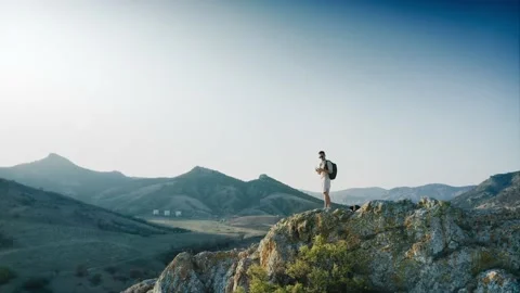 A hiker with a backpack climbed to the top of a mountain and launches a drone Stock Footage 217406069