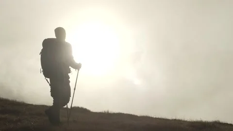 A hiker with a backpack climbs a mountain at sunset. Stock Footage 211815654