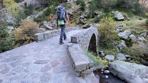 Hiker with backpack crossing a bridge on a mountain Stock-Footage 146316459