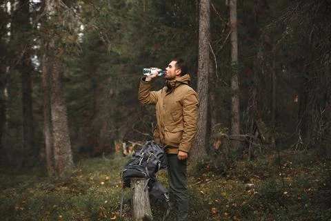 Hiker with backpack drinking water in deep forest Stock Photos