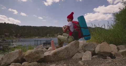 Hiker with Backpack Enjoys Lakeside View in Nature 스톡 동영상 323358766