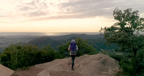 Hiker with backpack on his back watching sunrise from top mountain Stock Footage 147955549