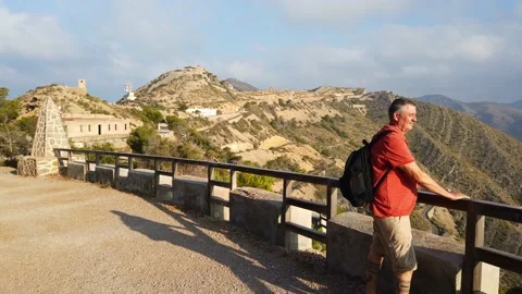 A hiker with a backpack looks out over the wide landscape at Cabo Tinoso. Stock Footage 138207357