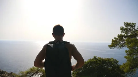 Hiker with backpack reaching up edge of mountain and raising his hands Stock Footage 135252667