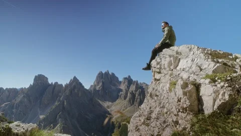 Hiker with backpack sitting on rock overlooking Lago di Braies Dolomites Stock Footage 320103630