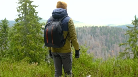 Hiker with backpack standing on mountain viewpoint overlooking forest valley Vídeos de archivo 322810216