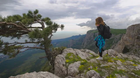 Hiker with backpack standing on top of the mountain and enjoying valley view Stock Footage 64026225
