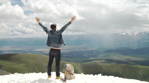 Hiker with backpack standing on top of a mountain with raised hands and enjoying Stock Footage 65484937