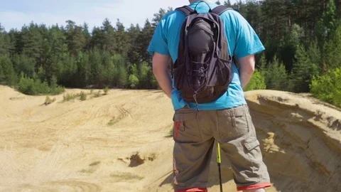 Hiker with backpack standing on top of a mountain. Sand dunes. Video stock 71256989