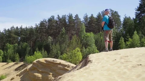 Hiker with backpack standing on top of a mountain. Sand dunes. Video stock 71257044