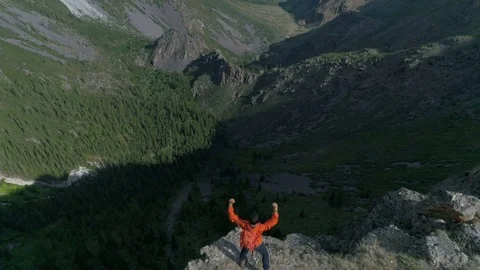 Hiker with backpack standing on top of a mountain aerial slow motion 4k Stock Footage 77874795