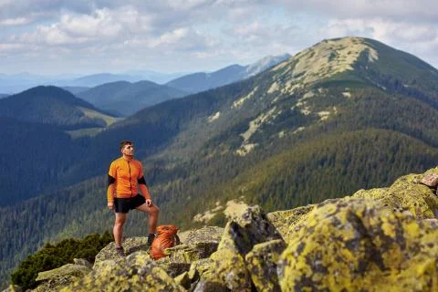 Hiker with backpack standing on top of a mountain with raised hands Stock Photos