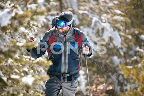 Hiker with backpack trekking in mountains. Cold weather, snow on hills. Winte Stock Photos