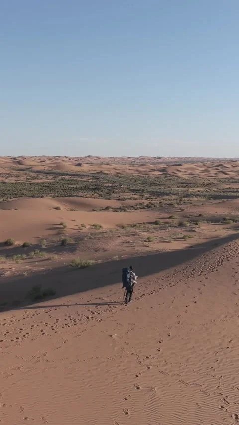Hiker with backpack walking on sand dune in Tengger Desert Видео 345368865