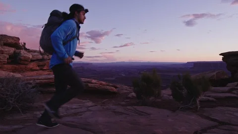 Hiker with Backpack walks to cliff edge and overlooks canyon Stock Footage 127147338