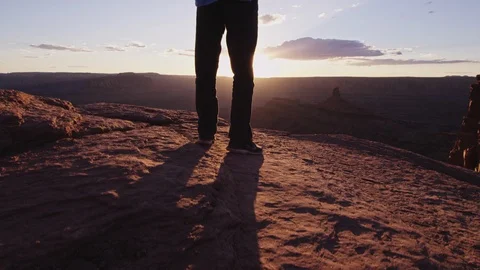 Hiker with Backpack walks to cliff edge and overlooks canyon Stock Footage 127458462