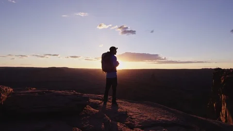 Hiker with Backpack walks to cliff edge and overlooks canyon Stock-Footage 127458580