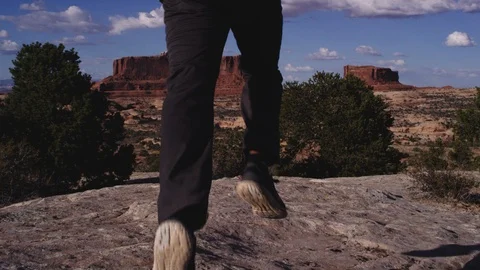 Hiker with Backpack walks to cliff edge and overlooks canyon Video stock 127458654