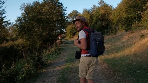 Hiker backpacking in hat walking  through the forest  and calling with him Stock Footage 82011752