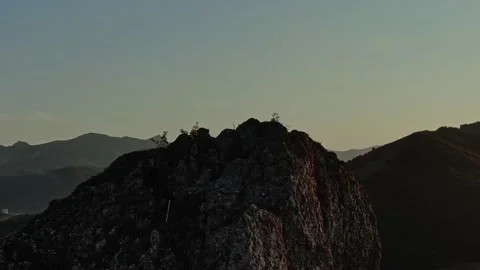 Hiker in Baseball Cap with Backpack and Walking Sticks Climbs a Rocky Top of a M Stock Footage 150591915
