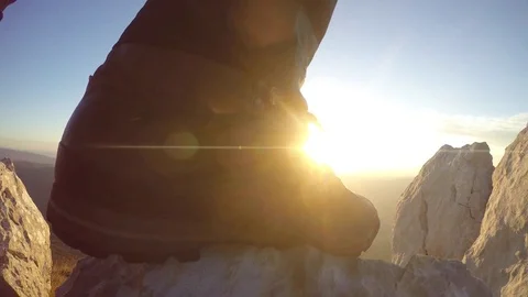 Hiker boot on the top of the mountain rock with sun at the background Stock Footage 82322650