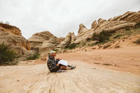Hiker in camo jacket checks his map in a desert arroyo basin Stock Photos