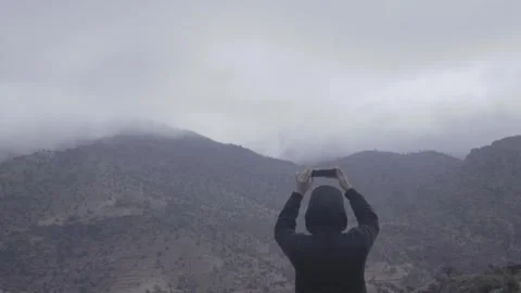Hiker Capturing Epic Misty Mountain Landscape on Smartphone Stockbeeldmateriaal 332774555
