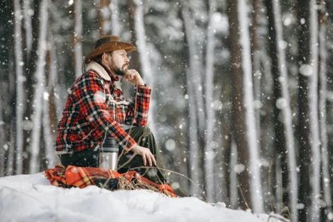 Hiker in Checkered Jacket Sitting on a Small Snowy Forest Hill Stock Photos