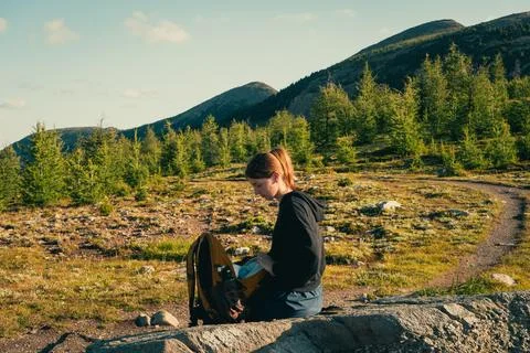 Hiker checking her backpack on a mountain trail Stock Photos