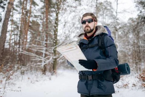 Hiker Checking Map to Orientate in Snow-clad Forest Stock Photos