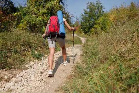 Hiker Climbing Up a Mountain Trail while Carrying a Backpack and Using a Stock Photos