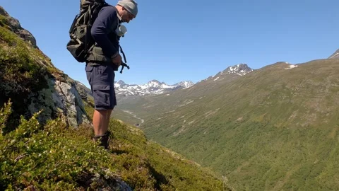 Hiker closes the strap of his backpack on mountainside Norway Stock Footage 156780714