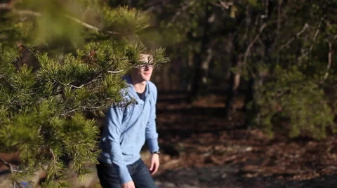 Hiker coming out from behind pine tree looking up Stock Footage 63880248