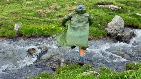A hiker crosses a fast alpine stream in Georgia Stock Footage 340388278