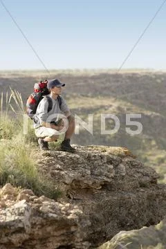 Hiker Crouching On Top Of Mountain Stock Photos